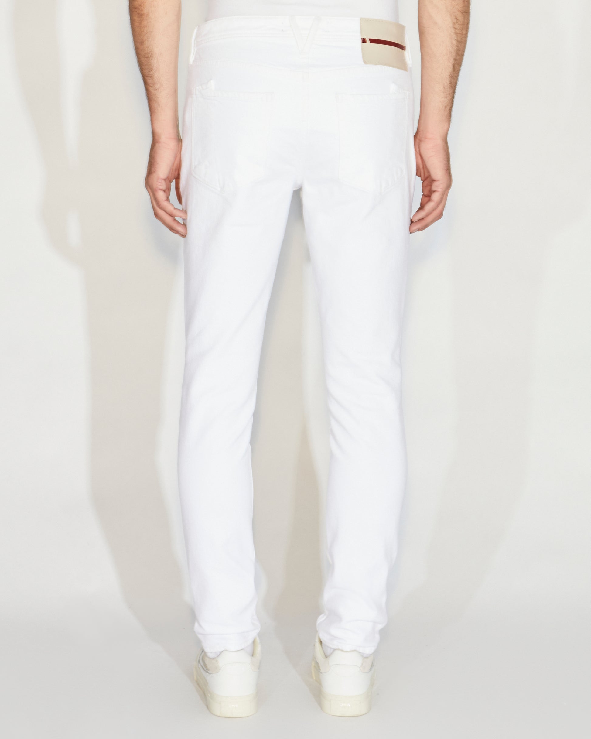 Man standing wearing white denim, a white tee and white shoes