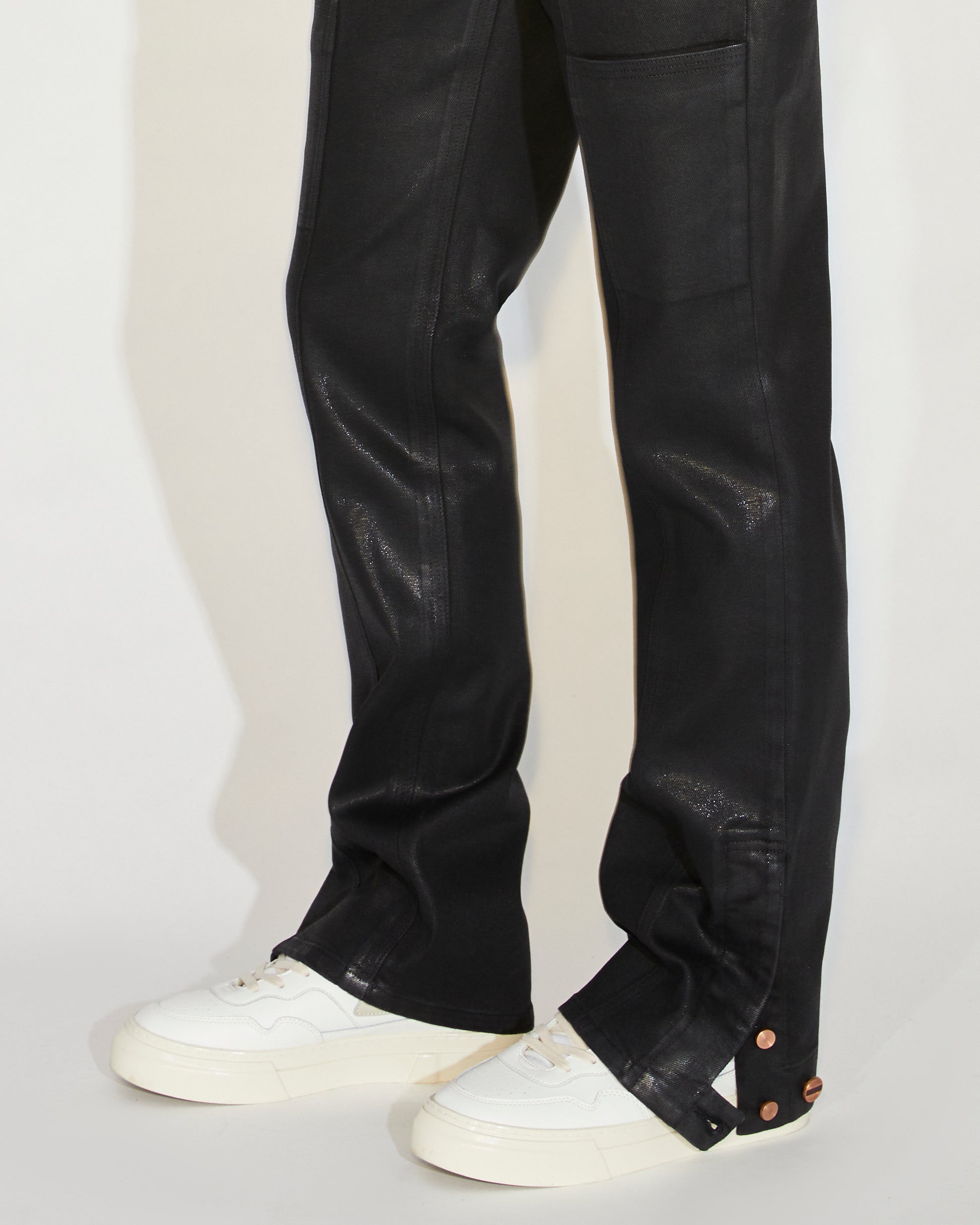 Man standing wearing black coated pants with a white tee and white shoes