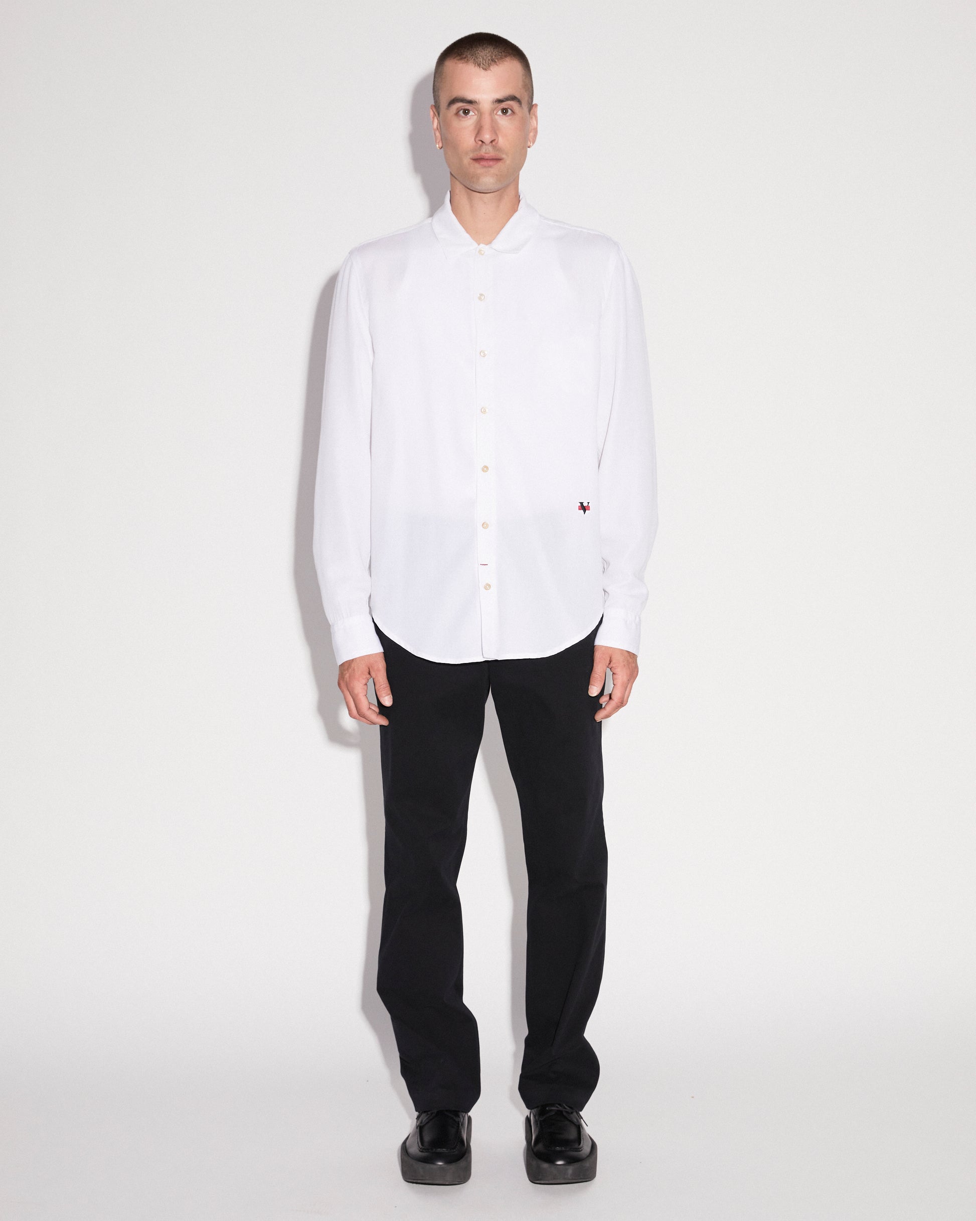Man standing wearing a white long sleeve button up shirt with black pants
